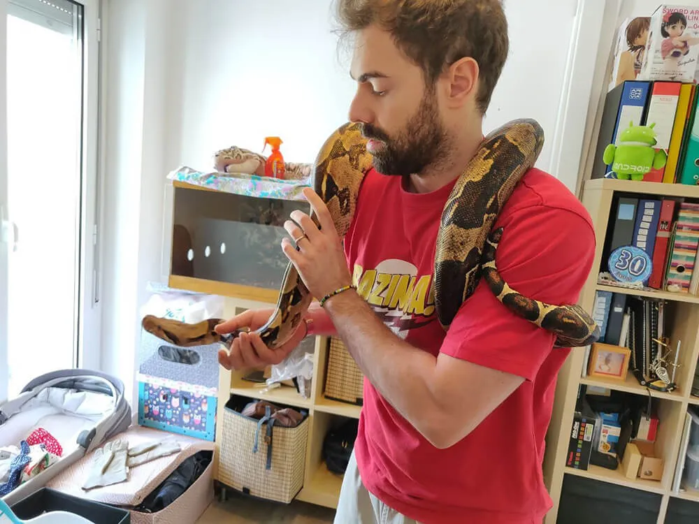 man with large snake draped around shoulders