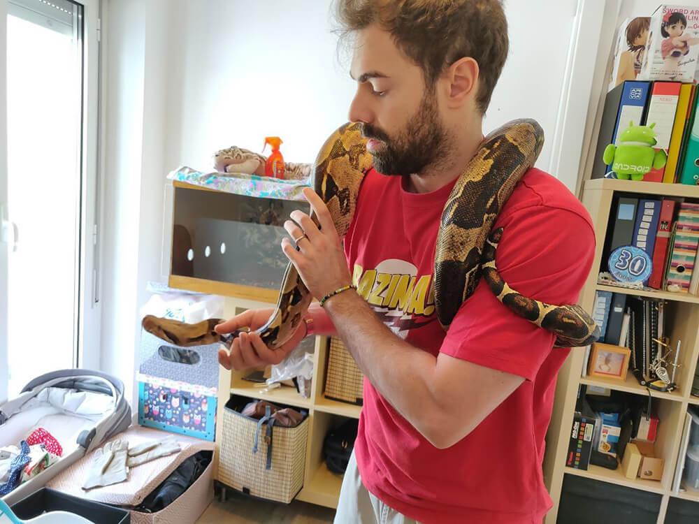 man with large snake draped around shoulders